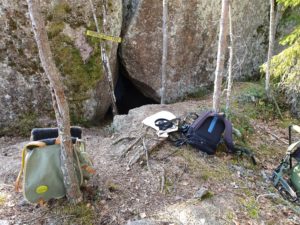 Ryggsäckar och liknande framför en grotta i skogen