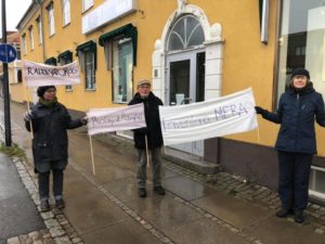 Tre personer står med banderoller utanför Skogsstyrelsens kontor. Det står: "Rädda vår skog", "Biologisk mångfald" och "Inventera MERA"