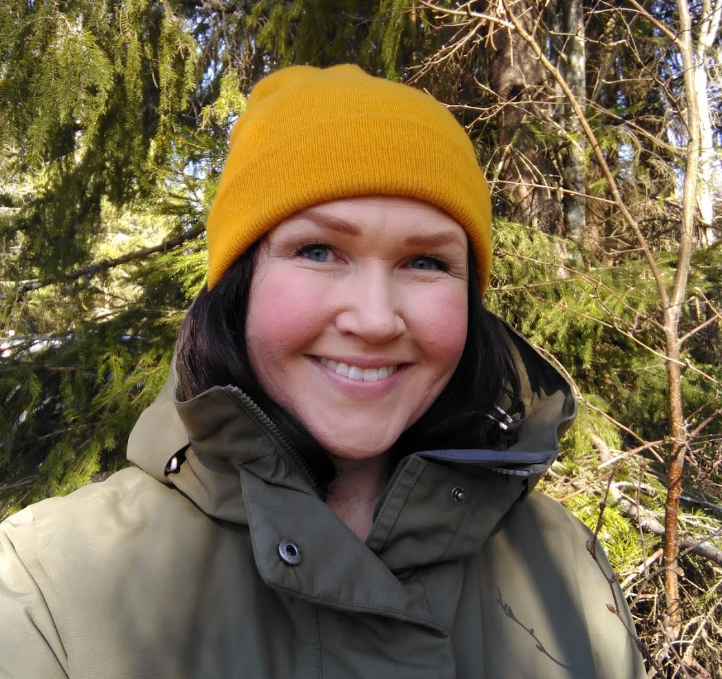 Elin i gul mössa och grön jacka i skogen